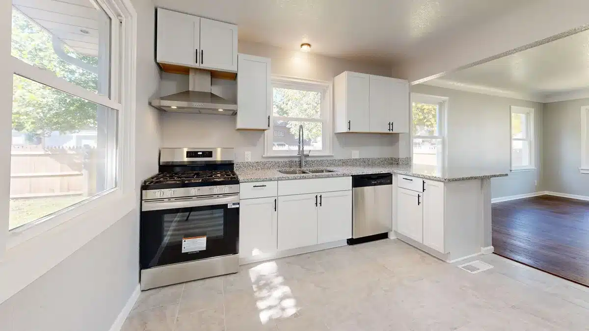 Cucina moderna luminosa con apertura verso la zona giorno e pannello trasparente divisorio.