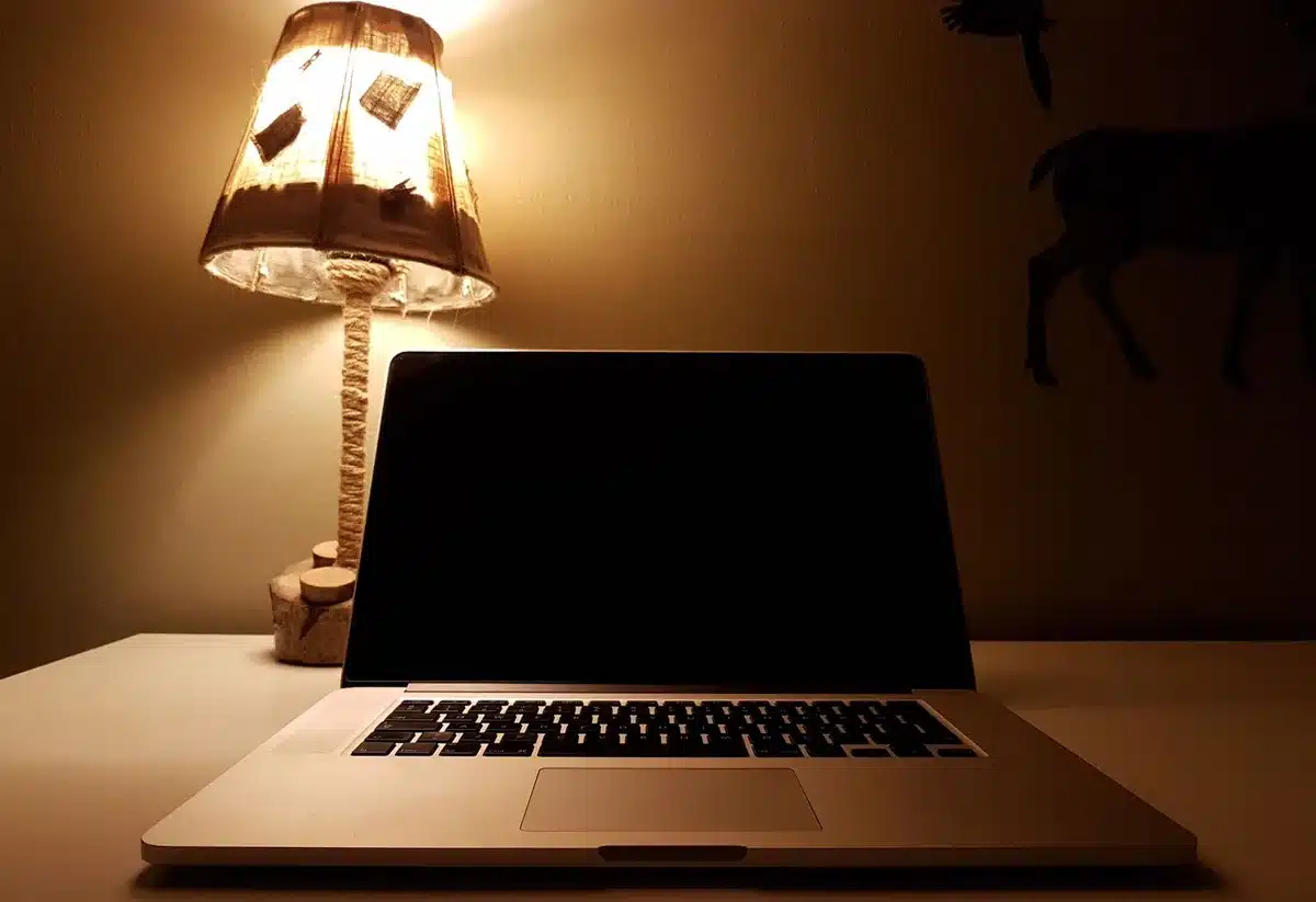 Lampada da scrivania orientabile che illumina il piano di lavoro accanto a un monitor
