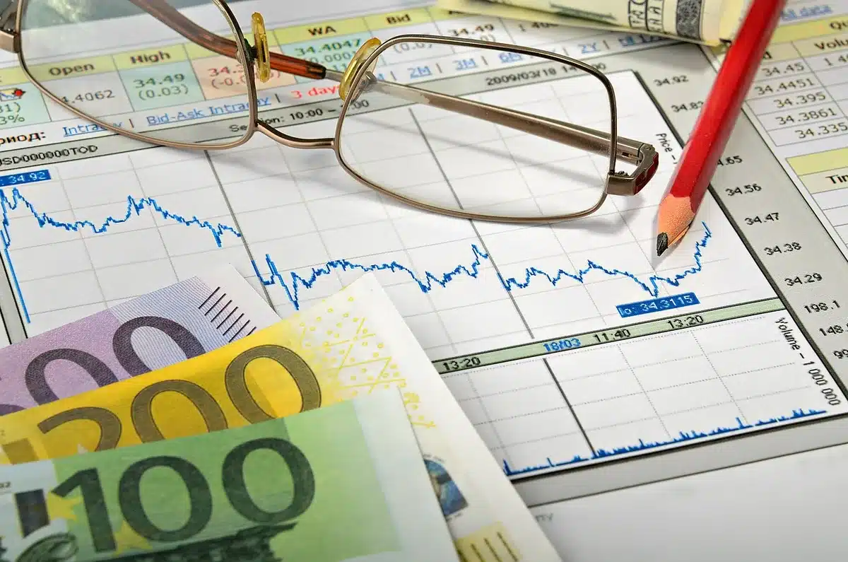 Banconote e monete euro su sfondo finanziario con dati di mercato