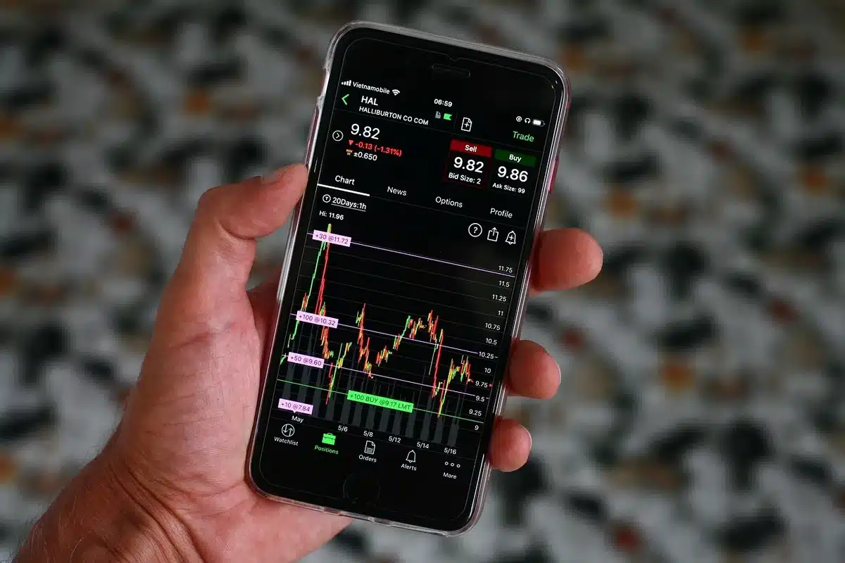 Schermi che mostrano oscillazioni di borsa e un trader che osserva i dati