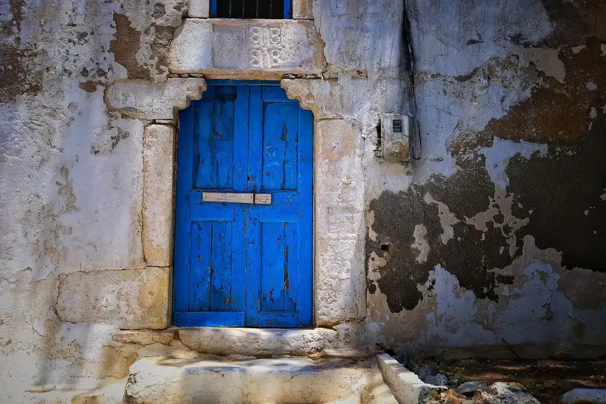 Interno di rustico con parete trattata a calce colorata e porta in legno restaurata