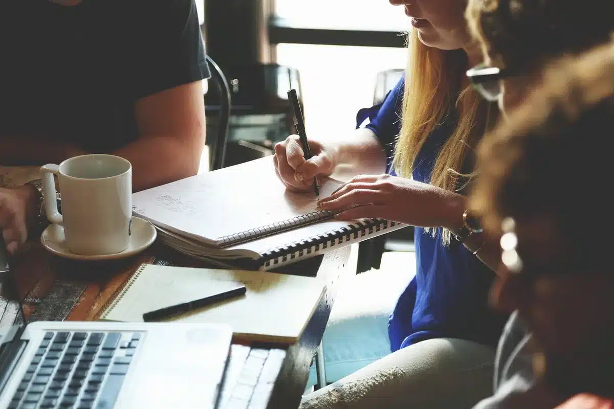 Riunione di investitori attorno a un tavolo con documenti finanziari e grafici di dati sportivi su schermi digitali