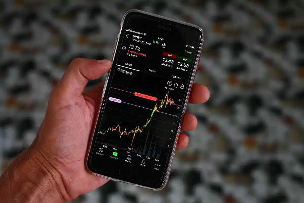 Operatore al desk di trading monitora grafici e dati finanziari su schermi durante seduta di borsa