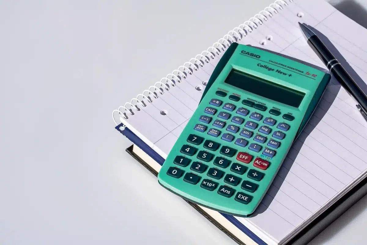 Mani anonime su moduli e calcolatrice su una scrivania, istituto finanziario
