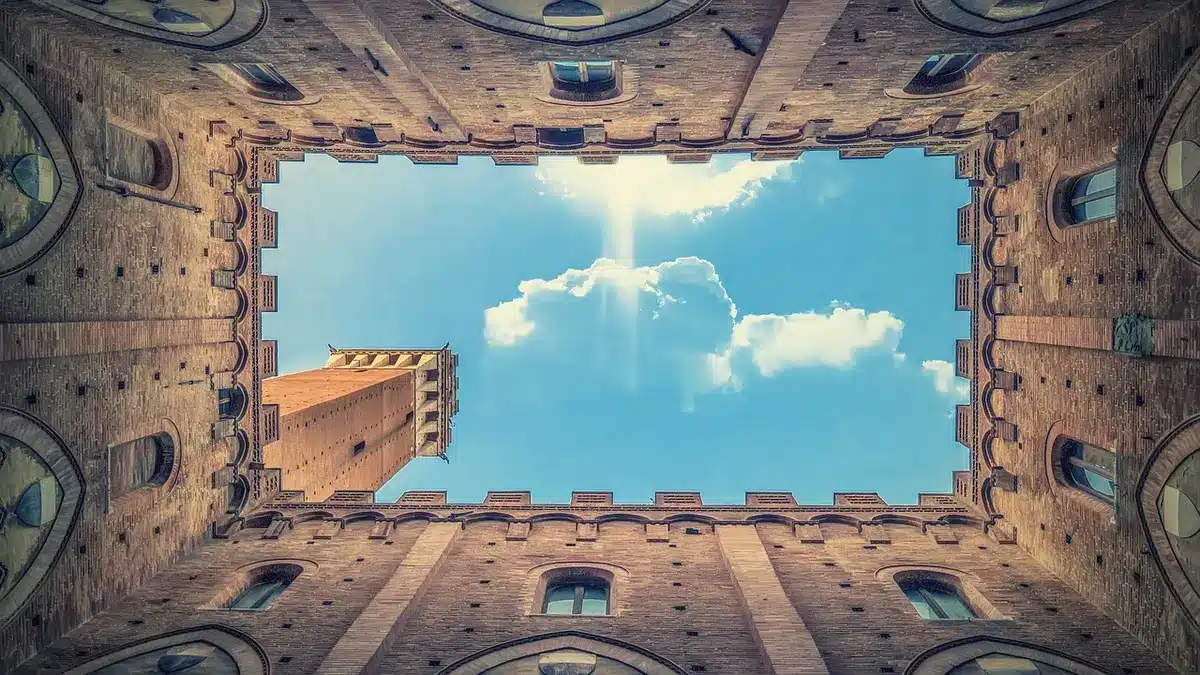 Piazza di Siena al crepuscolo con facciata bancaria e documenti anonimi in primo piano