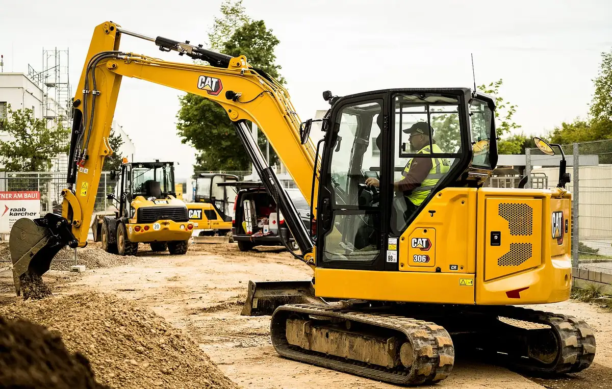 Mani che tengono planimetrie e appunti con modello di cantiere sullo sfondo